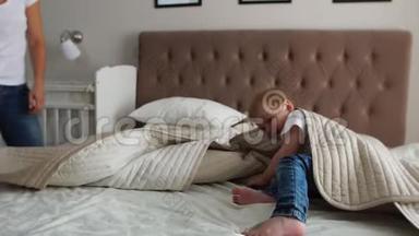 年轻的母亲和父亲带着她两岁的小儿子穿着睡衣，在床上放松和玩耍